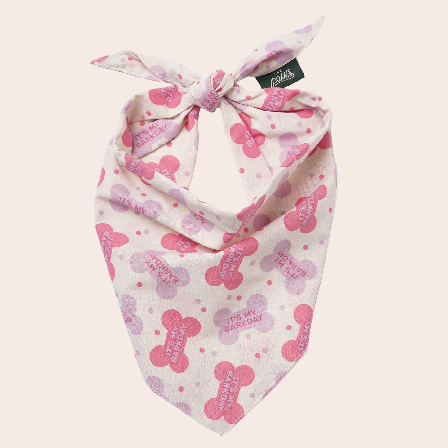 Pink and white dog bandana with bone designs and text on a white background